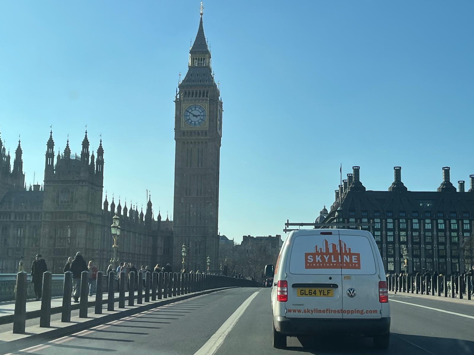 A company van crossing Westminster Bridge with the Houses of Parliament behind